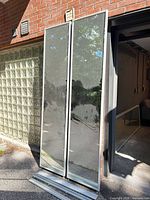 Front view of two mirrored sliding door panels leaning against wall