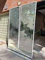 pair of mirrored doors leaning upright showing reflective surfaces and frames