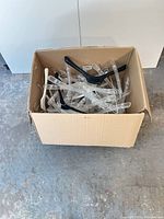 Box containing assorted clear, white and black plastic hangers