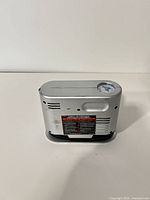 Side view of silver portable tire inflator showing caution label and overall shape