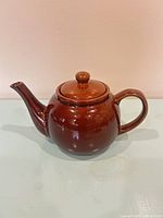 Left side view of brown glazed ceramic teapot with lid