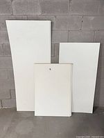 Three sizes of white bristol boards leaning against wall