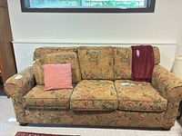 Full front view of floral sofa with pillow and throw