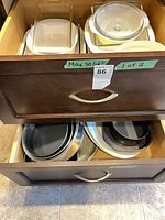 Drawer showing glass baking dish with lid and stacked white casseroles beneath
