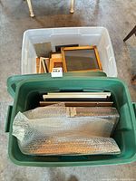 Top view of two storage totes holding stacked picture frames