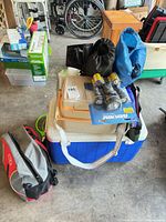 Group shot showing stacked coolers, flashlights, bug zappers, chairs in bags