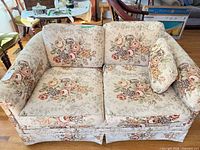 front view of cream floral loveseat with cushions and pillow