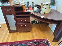 Overall view of dark brown laminate corner computer desk with drawers, cabinet, shelving and curved return