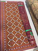 Both rugs, one fully laid out, other rolled beside couch