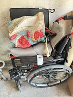 Folded red Karma wheelchair with cushion and tote bag