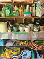 Shelves with garden chemicals, assorted plant pots, watering can, soil bags, hose and nozzle