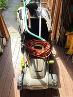 Top view of LawnMaster mower with extension cord, hedge trimmer blade and hand saw visible
