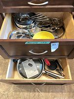 Overview of drawers with nested stainless and nonstick pans, glass lids visible