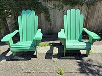 Pair of green painted wood Adirondack chairs front view on patio