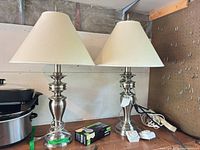 Pair of brushed nickel lamps with shades, bulbs box, cords visible