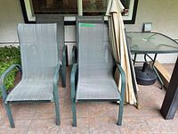 Two sling chairs, umbrella, additional chairs partially visible