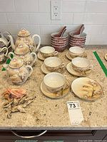 Full set on countertop showing teapots, cups, saucers, bowls and spoons