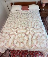 Bed fully assembled with quilt, pillows and wood headboard visible