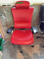 Front view showing red faux leather seat, headrest, armrests, base with casters