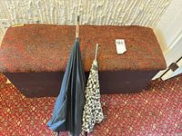 Bench top showing paisley fabric and lot tag with umbrellas leaning