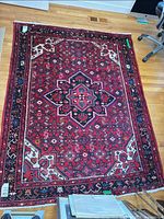 Full view of red Persian rug on hardwood floor