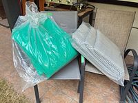 Both aluminum chairs stacked with wrapped green and striped cushions placed on seats