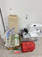 Group shot of two sewing machines (one visible, one in red case), fabrics, accessory box, manual, pedal