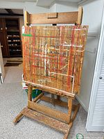 Front view of wooden easel holding paint-splattered backer board