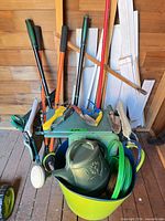 Overview of kneeler bench with long-handled tools, trowels, bucket, watering can and hose