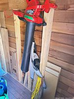 Toro blower/vacuum with long black tube and collection bag hanging on wall