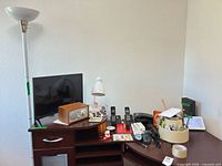 overall view of floor lamp, desk lamp, monitor, radio, phones and organizer on desk