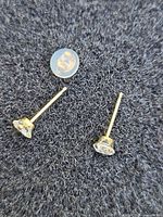 Pair of gold stud earrings with cubic zirconia, one silicone back shown
