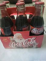 Front view of six unopened Coca-Cola Classic 1999 holiday bottles in original carrier