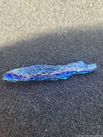 Top view of elongated iridescent blue kyanite blade showing surface texture and metallic sheen