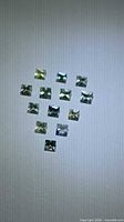 Front view of twelve square princess-cut sapphires arranged, showing size and color mix