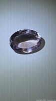Oval faceted pink-purple amethyst on neutral background