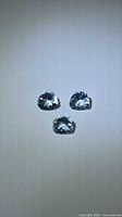 Three pear-cut aquamarines on neutral background