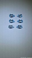 Six pear-cut blue topaz gemstones aligned vertically