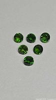 Six round green gemstones on neutral background