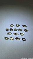 Group of 15 oval yellow tanzanite gemstones displayed on neutral background