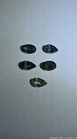 Five pear and oval cut sapphires arranged on flat surface
