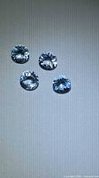 Four round blue gemstones on neutral background