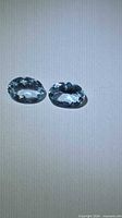Two oval cut aquamarines on neutral background