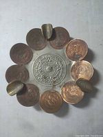Top view showing Aztec calendar center, eight coins, three brass rests