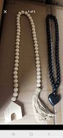 Natural unfinished wood bead garland with house accent and tassel beside black bead garland with heart pendant