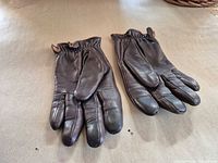 Pair brown leather gloves front view on surface