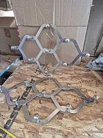 Two diamond lattice brushed nickel racks on plywood surface
