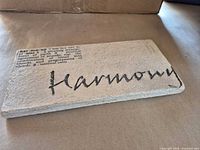 Front angled view showing text “Harmony” and dictionary definition, surface texture