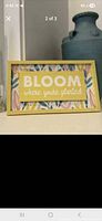 Yellow framed Bloom sign on tabletop