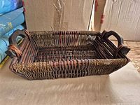 Top angled view of rectangular wicker basket with wood handles